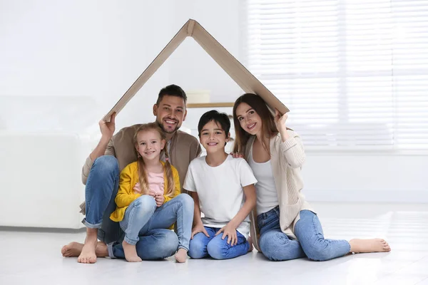 Lycklig familj sitter under kartongtak hemma. Försäkringsavtal — Stockfoto