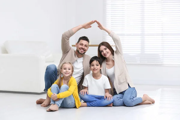 Glad familj bildar hus tak med händerna hemma. Försäkring — Stockfoto