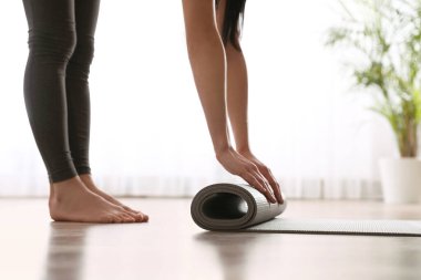 Stüdyoda yoga minderi yuvarlayan kadın, yakın plan.