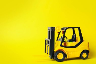 Sarı arka planda oyuncak forklift, mesaj için boşluk. Lojistik ve toptan satış kavramı