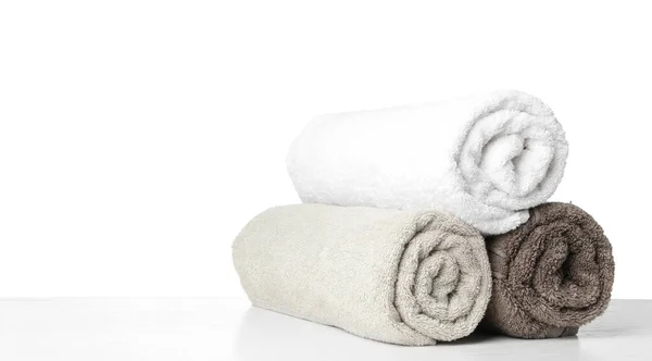 Прокат свежие чистые полотенца для ванной комнаты на столе против белого ba — стоковое фото
