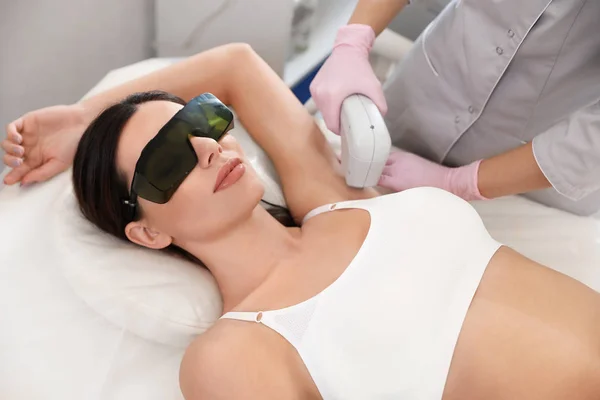 Young woman undergoing laser epilation procedure in beauty salon — Stock Photo, Image