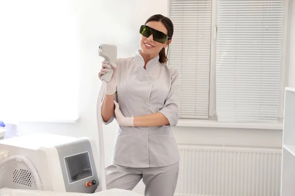 Mladá žena drží profesionální laser epilátor v salonu krásy — Stock fotografie