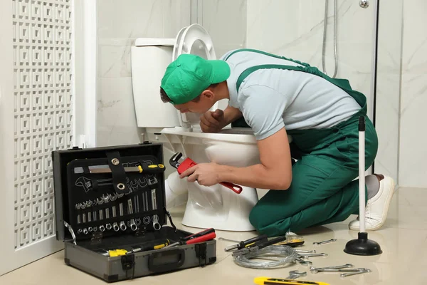 Professional plumber repairing toilet bowl in bathroom — Stock Photo, Image