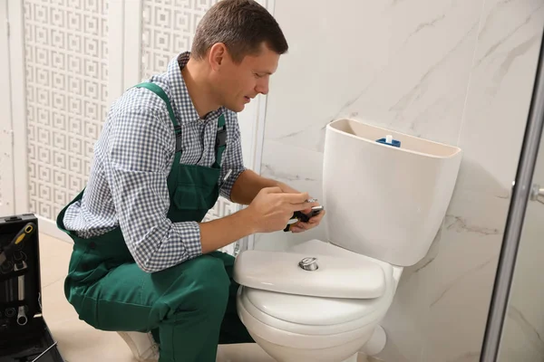 Profissional encanador reparação vaso sanitário no banheiro — Fotografia de Stock