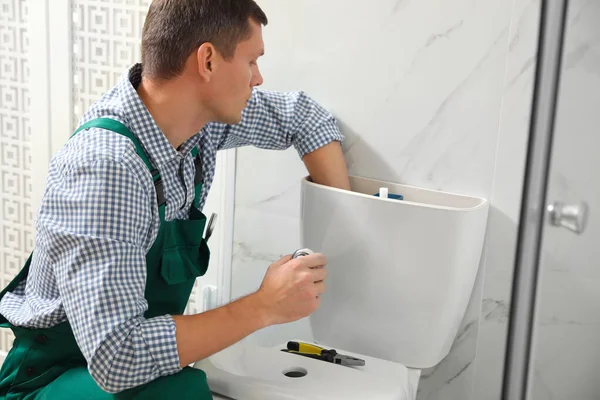 Professionele loodgieter repareren toilet kom in de badkamer — Stockfoto
