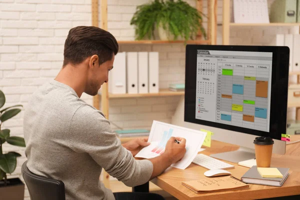 Homme travaillant avec calendrier à la table dans le bureau — Photo