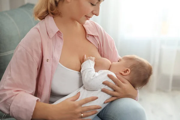 Mujer joven amamantando a su bebé en casa — Foto de Stock