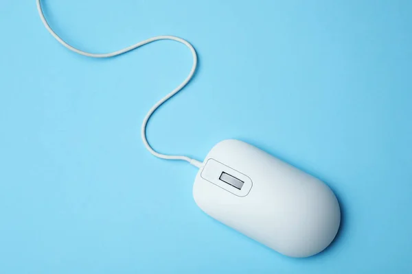 Wired computer mouse on light blue background, top view