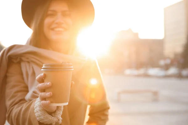 Mujer joven con taza de café en la calle de la ciudad por la mañana, enfoque — Foto de Stock