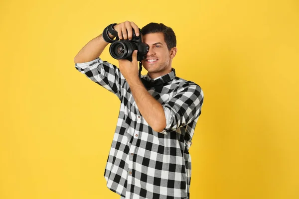 Professional photographer working on yellow background in studio — Stock Photo, Image