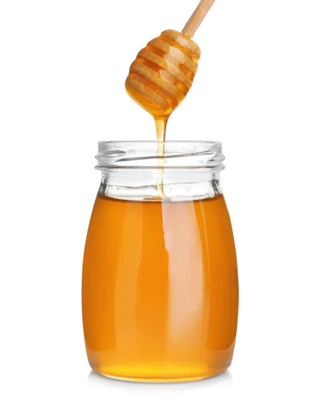 Honey dripping from wooden dipper into jar isolated on white — Stock Photo, Image