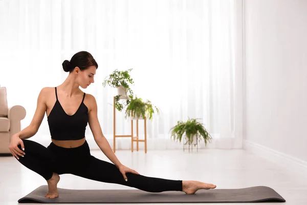 Professionele jonge acrobaat die thuis yoga beoefent — Stockfoto