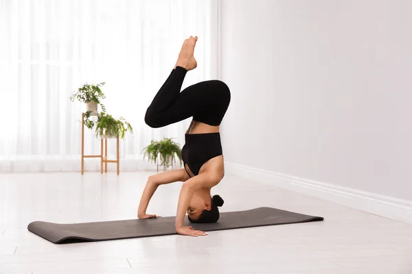 Professionelle junge Akrobatin praktiziert Yoga zu Hause — Stockfoto