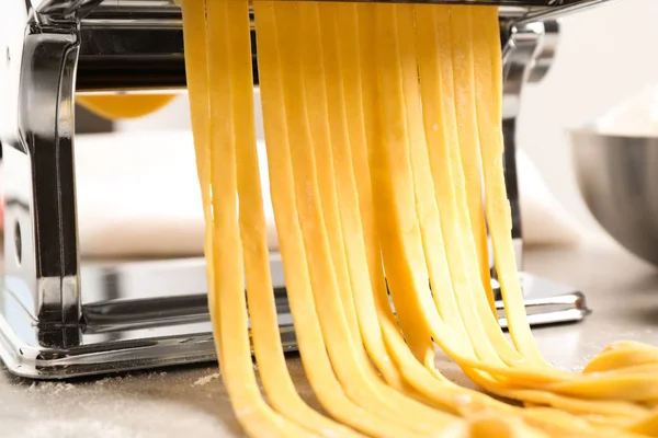 Pasta maker machine met deeg op grijze tafel, close-up — Stockfoto