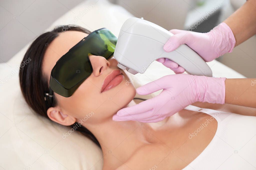 Young woman undergoing laser epilation procedure in beauty salon