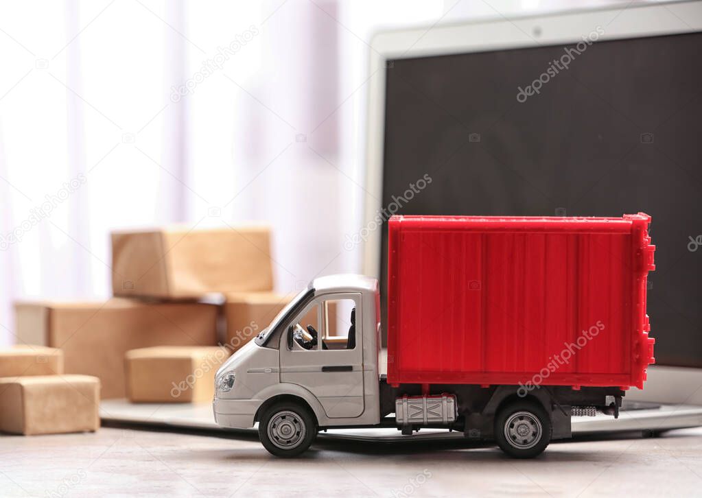 Toy truck near laptop on table. Logistics and wholesale concept