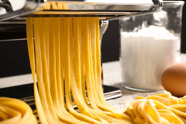 Pasta maker machine met deeg en producten op tafel, close-up — Stockfoto