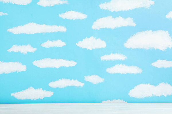 White wooden table near wall with painted blue sky. Idea for bab