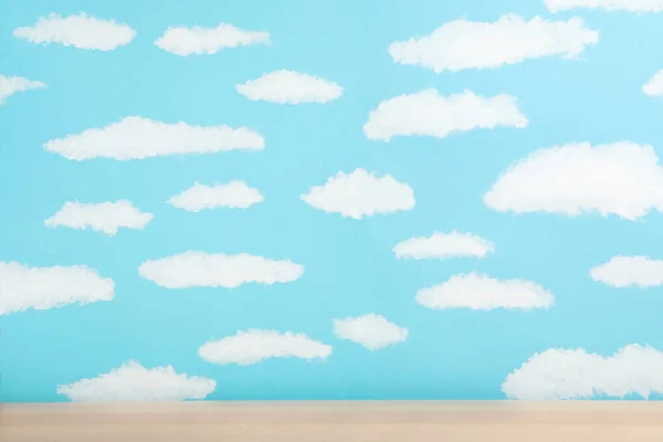 Wooden table near wall with painted blue sky. Idea for baby room — Stock Photo, Image