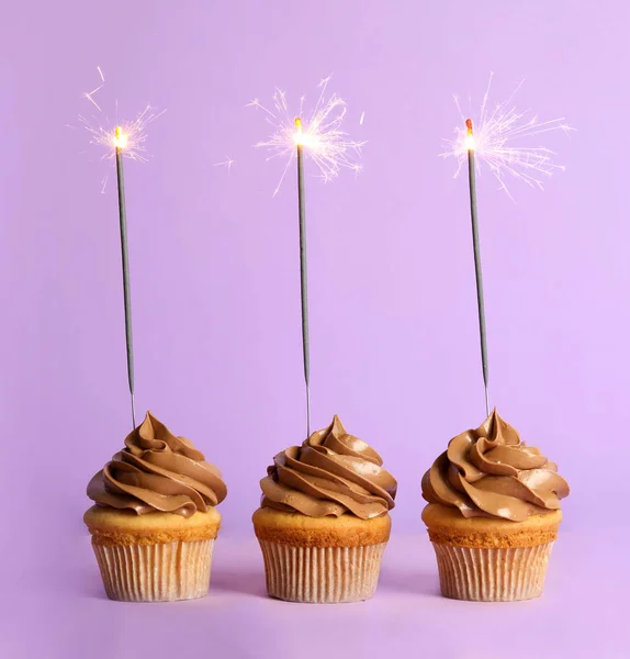 Magdalenas de cumpleaños con bengalas sobre fondo violeta —  Fotos de Stock