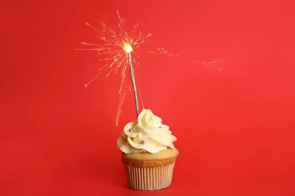 День рождения кекс с искрой на красном фоне — стоковое фото