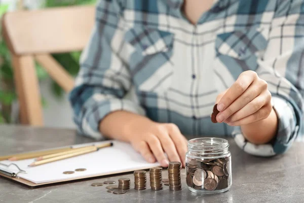 Γυναίκα βάζοντας χρήματα σε γυάλινο βάζο στο τραπέζι, closeup — Φωτογραφία Αρχείου