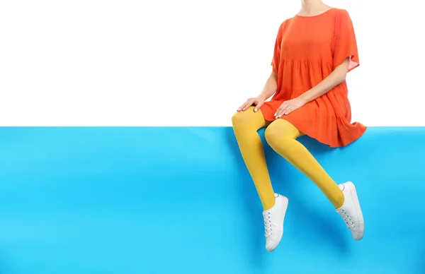 노란 스타킹을 하고 멋진 신발을 신고 있는 여자 B 색에 앉아 있는 — 스톡 사진