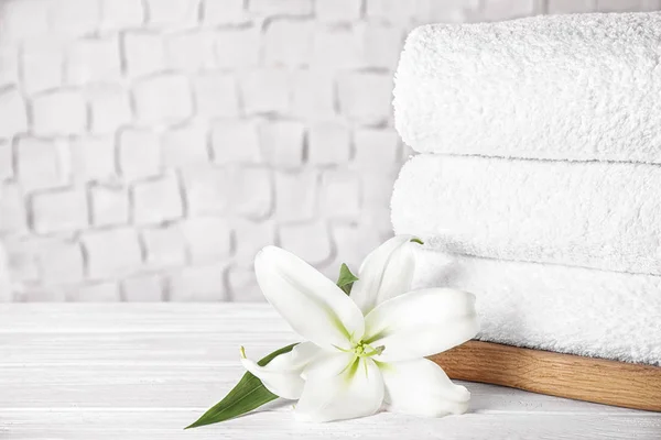 Hromada čistých ručníků a krásné květiny na bílém dřevě — Stock fotografie