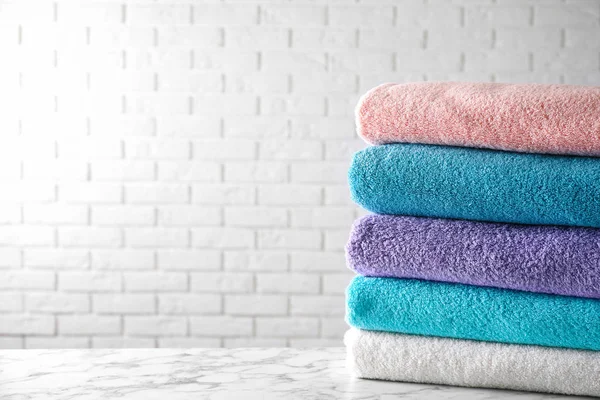 Pilha de toalhas de banho limpas na mesa de mármore branco. Espaço para texto — Fotografia de Stock