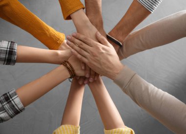 Gri taş arka planda el ele tutuşan insanlar, üst manzara. Birlik kavramı