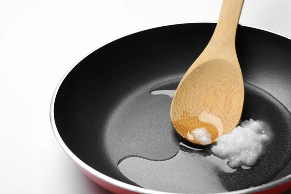 Сковородка с кокосовым маслом и деревянной ложкой на белом фоне — стоковое фото