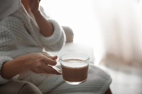 Mujer con taza de bebida caliente en el sofá en casa por la mañana, primer plano — Foto de Stock