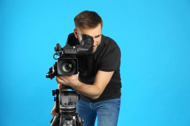 Mavi arkaplanda profesyonel video kamerası olan operatör