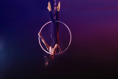 Genç bir kadın hava halkası üzerinde akrobatik bir element sergiliyor. 