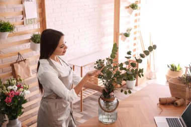 Atölyede yeşil dalları olan bir çiçekçi.