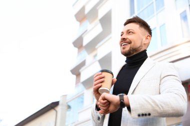 Sabah şehir caddesinde elinde bir fincan kahve olan bir iş adamı.