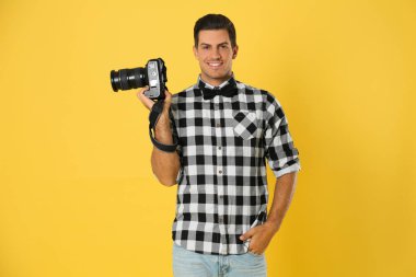 Stüdyoda sarı arka plan üzerinde çalışan profesyonel fotoğrafçı.