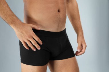 Man in black underwear on light grey background, closeup