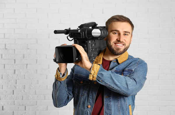 Operator with professional video camera near white brick wall — Stock Photo, Image