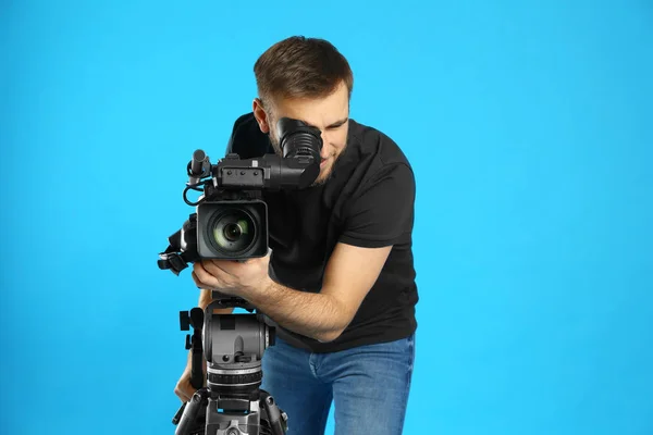 Opérateur avec caméra vidéo professionnelle sur fond bleu — Photo