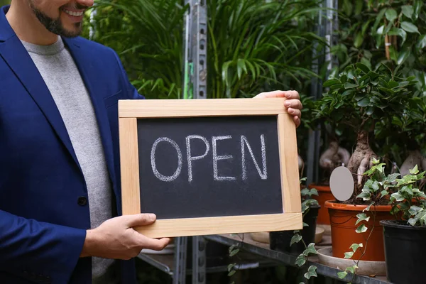 Propietario de un negocio masculino sosteniendo el cartel OPEN en su floristería, closeu — Foto de Stock