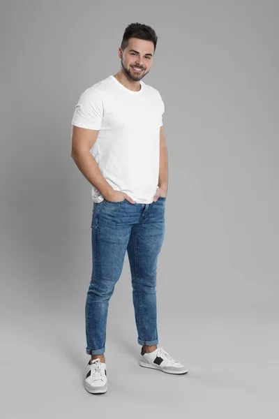 Hombre joven en jeans con estilo sobre fondo gris — Foto de Stock