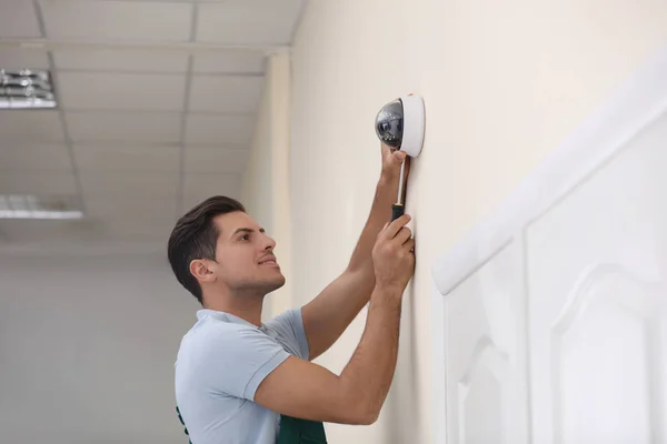 Techniker installiert Videokamera an Wand in Innenräumen — Stockfoto