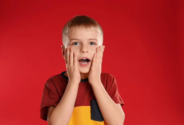 Porträt eines überraschten kleinen Jungen auf rotem Hintergrund — Stockfoto