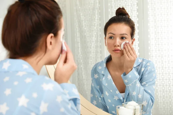 Adolescente chica con acné problema de limpieza de su cara cerca de espejo en murciélago — Foto de Stock