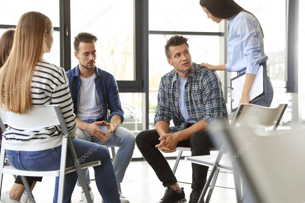 Psychotherapist working with patients in group therapy session indoors