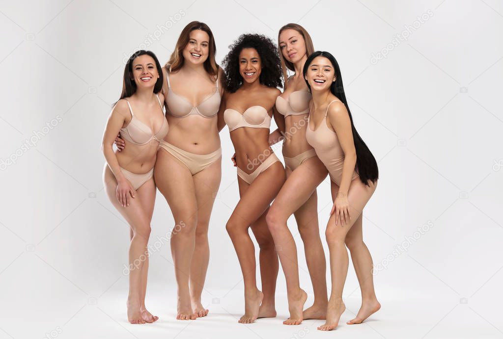 Group of women with different body types in underwear on light background