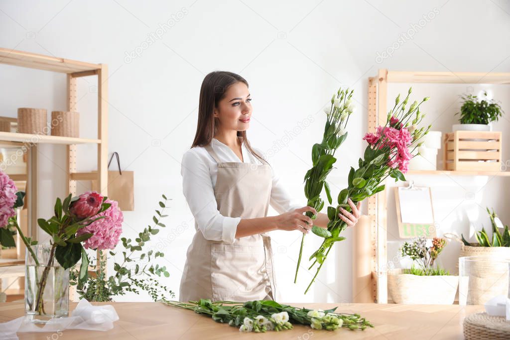 Florist making beautiful bouquet at table in workshop