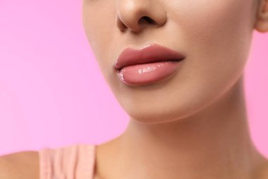 Pembe arka planda parlak rujlu kadın, yakın plan.